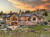Stunning exterior of a luxury home with stone accents, solar panels, and beautiful landscaping against a vibrant sunset sky at 750 Left Fork Rd, Boulder, CO 80302