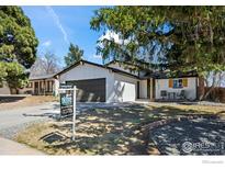 Charming home featuring white brick, gray garage door, covered porch and a well-manicured lawn at 8334 Allison Ct, Arvada, CO 80005