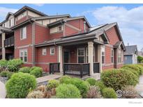 Inviting home featuring a charming front porch, complemented by fresh landscaping and solar panels on the roof at 860 Widgeon Dr, Longmont, CO 80503