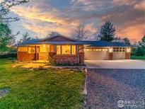 Charming single-story home with brick accents, lush lawn, and attached two car garage at dusk at 11361 Flatiron Dr, Lafayette, CO 80026