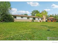Spacious backyard featuring a lawn, a gazebo, and the back of the house with brick accents at 12734 Anhawa Ave, Longmont, CO 80503