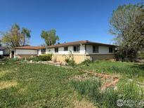 Modest single-story home features a brick foundation, a clean white facade, and a well-lit interior with verdant landscaping at 12734 Anhawa Ave, Longmont, CO 80503