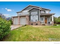 Charming two-story home featuring a manicured lawn, stone accents, and a convenient three-car garage at 2193 Sand Dollar Cir, Longmont, CO 80503