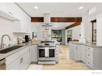 Bright, modern kitchen with stainless steel appliances and wooden beam accents, open to a dining area at 4100 Greenbriar Blvd, Boulder, CO 80305