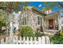 Charming stone-clad home with a manicured front yard, a white picket fence, and a welcoming front porch at 5134 Ladies Tresses Pl, Broomfield, CO 80023