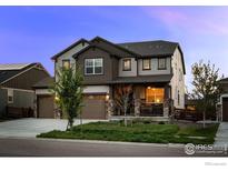Charming two-story home with a three-car garage, well-maintained lawn, and covered front porch at 647 Boulder Peak Ave, Erie, CO 80516
