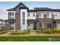 Modern townhome showcasing a brick and corrugated metal exterior with manicured landscaping and inviting front porch at 9305 S Gore St # C, Arvada, CO 80007