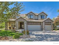 Beautiful home with a three-car garage, stone accents, manicured lawn, and covered front porch at 14180 Whitney Cir, Broomfield, CO 80023