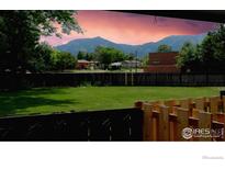 A serene backyard with a lush lawn, wooden fence, and a stunning mountain view at 4150 Monroe Dr # C, Boulder, CO 80303