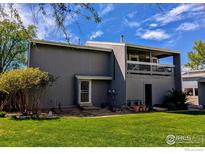 Two-story grey home featuring a balcony, manicured lawn, and mature trees at 4150 Monroe Dr # C, Boulder, CO 80303