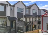Stylish townhome featuring a gray brick facade, covered porch and second story balcony at 5173 Vivian St, Wheat Ridge, CO 80033