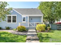 Charming blue home with landscaped front yard and inviting entryway steps at 725 Arrowood St, Longmont, CO 80503