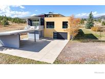 Modern home featuring unique architecture, yellow accents, and an attached garage and carport at 987 Lost Angel Rd, Boulder, CO 80302