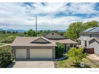 Well-maintained home boasts a three-car garage, lush green lawn, and views of the mountains in the distance at 1264 Banner Cir, Erie, CO 80516
