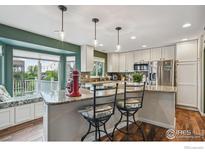Bright kitchen with granite countertops, stainless steel appliances, a breakfast bar and a window seat at 13106 Elizabeth St, Thornton, CO 80241