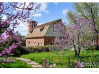 Unique brick home with gambrel roof, silo, and lush, mature landscaping under a bright blue sky at 1341 N 95Th St, Lafayette, CO 80026