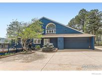 Charming blue two-story home with a front yard featuring mature trees and a spacious driveway at 2485 Lee Hill Dr, Boulder, CO 80302