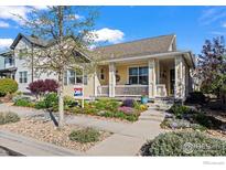Charming home with a welcoming front porch and beautifully landscaped front yard with vibrant flowers and shrubs at 2827 Twin Lakes Cir, Lafayette, CO 80026