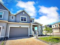 Charming two-story home featuring a covered front porch, gray siding, and a spacious two-car garage at 700 Lillibrook Pl, Erie, CO 80026