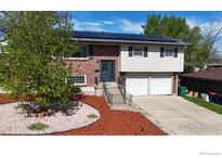 Two story home showcasing a brick facade and siding, solar panels, landscaped front yard and a two car garage at 8351 Ralph Ln, Denver, CO 80221