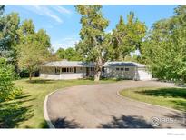 Charming single-story house with a circular driveway and lush green landscaping at 8813 Baseline Rd, Lafayette, CO 80026
