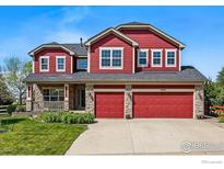 Charming two-story home featuring red siding, stone accents, and a well-manicured lawn under a clear blue sky at 2290 Cottonwood Pl, Erie, CO 80516