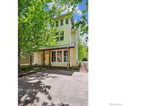 Charming two-story home showcasing a light yellow exterior, welcoming porch and mature shade trees at 2602 Tumwater Ln, Boulder, CO 80304