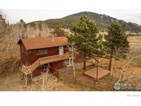 Two-story home with a deck, wood siding, and mature trees, nestled in a mountain landscape at 26167 De Berry St, Conifer, CO 80433