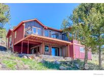 Charming home featuring a spacious deck, metal and wood exterior accents and set on a grassy, sloping lot at 548 Coughlin Meadows Rd, Boulder, CO 80302