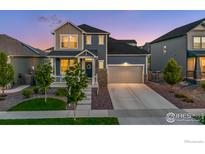 Beautiful two-story home boasts a two-car garage, covered front porch, and charming landscaping at 5782 Slate River Pl, Brighton, CO 80601