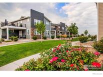 Beautiful townhome exterior featuring manicured landscaping, flowers, and a pleasant view at 749 Robert St, Longmont, CO 80503
