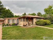 Charming single-story home with a well-manicured lawn and flower beds at 1235 Lincoln St, Longmont, CO 80501