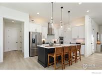 Bright kitchen boasts a large island with seating, stainless steel appliances, and stylish pendant lighting at 1611 Poplar, Erie, CO 80516