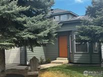 Charming two-story home with sage siding, an orange front door, mature trees, and a manicured lawn at 1695 Parkside Cir, Lafayette, CO 80026