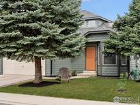 Charming home with a well-maintained lawn, an orange front door, and mature trees in the front yard at 1695 Parkside Cir, Lafayette, CO 80026