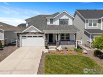 Charming two-story home with stone accents, a covered porch, landscaped yard, and an attached two-car garage at 1923 High Plains Dr, Longmont, CO 80503