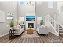 Bright living room with a fireplace, a television, large windows, and modern decor at 1923 High Plains Dr, Longmont, CO 80503