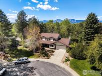 Two story home with neutral siding, brick accents, mature trees, a long driveway, and mountain views at 4311 Pali Way, Boulder, CO 80301