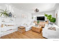 Bright living room features hardwood floors, white sofas, plants, and a rustic wood coffee table at 4401 Vrain St, Denver, CO 80212