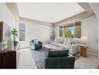 Bright living room featuring neutral paint, two green chairs, a gray sofa, and multiple large windows at 708 Teal Cir, Longmont, CO 80503