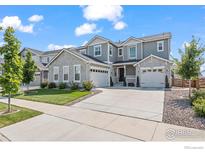 Charming gray two-story home featuring a stone facade, well-manicured lawn, and an inviting two-car garage at 832 Sundown Way, Erie, CO 80516