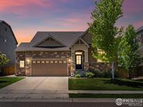 Charming single-Gathering home with a stone facade, well-manicured lawn, and an attached two-car garage at 950 Sumner Way, Erie, CO 80516