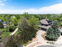 An aerial view showcases a landscaped property with mature trees, solar panels, and a winding driveway at 982 Walnut Ct, Louisville, CO 80027