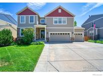 Charming two-story home featuring a three-car garage, a well-manicured lawn, and a blend of stone and siding accents at 10048 Granby St, Commerce City, CO 80022
