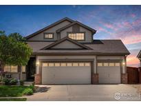 Charming two-story home with a three car garage and brick accents set against a colorful evening sky at 10553 Joplin St, Commerce City, CO 80022
