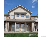 Traditional townhome exterior featuring stone accents and a well-maintained lawn at 10818 Cimarron St # 206, Firestone, CO 80504