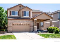 Two-story home with brick accents, a two-car garage, and a covered front porch at 13972 Monroe St, Thornton, CO 80602