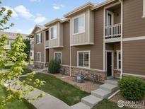 Inviting townhome featuring a well-maintained lawn, stone accents and private balcony at 1456 Sepia Ave, Longmont, CO 80501
