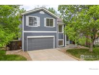 Charming two-story home with a gray exterior, white trim, and a well-maintained front yard at 1724 Holeman Dr, Erie, CO 80516