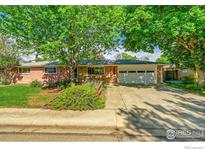 Charming single-story home with a well-manicured lawn, mature trees, and a two-car garage at 1800 Atwood St, Longmont, CO 80501